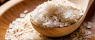 Натуральный скраб для лица с сахаром, кофе и овсянкой на деревянной ложке на светлом фоне